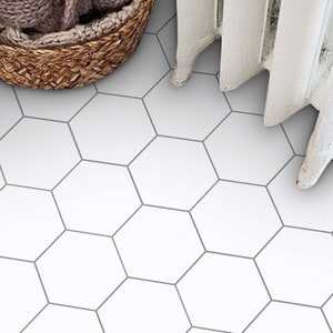 Puede incluir: Azulejos hexagonales blancos con líneas de lechada grises. Los azulejos están dispuestos en un patrón repetitivo.