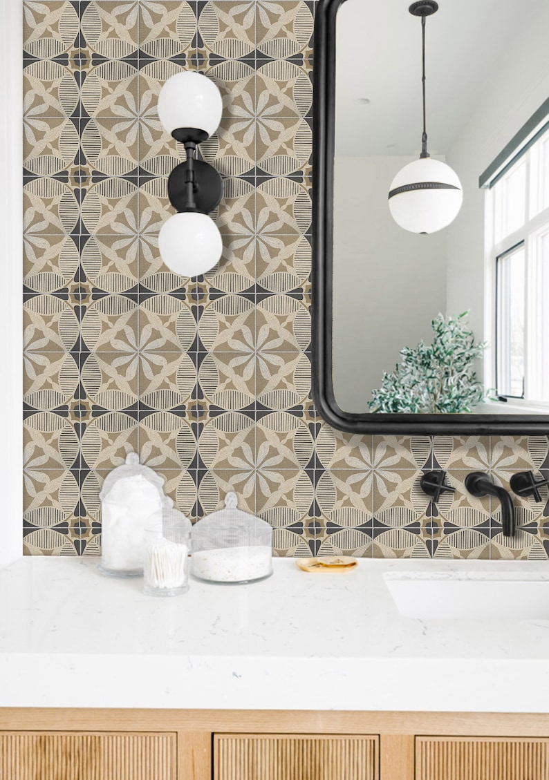 May include: A bathroom vanity with a white countertop and a black framed mirror. The walls are tiled with a geometric pattern in shades of brown and black. There are two glass jars on the countertop, one with cotton swabs and the other with cotton balls. The vanity has two wooden drawers.