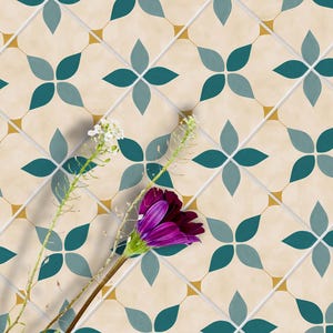 May include: A close-up of a cream-colored tile floor with a repeating pattern of teal blue and gray four-leaf clover shapes. A single purple flower with green leaves is in the foreground.