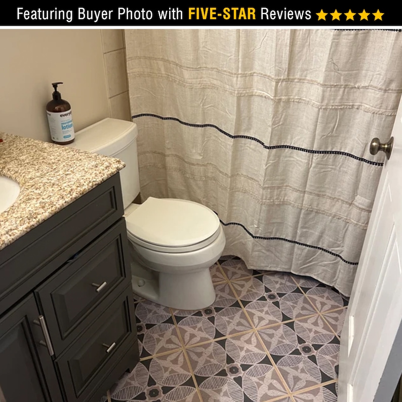 May include: A bathroom with a white toilet, a dark gray vanity with drawers, and a white shower curtain with black stripes. The floor is tiled with a geometric pattern in shades of pink, black, and white.
