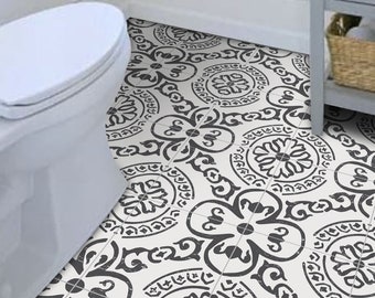 May include: Bathroom floor tiles with a black and white floral pattern. The tiles are square and arranged in a grid, creating a repeating design. The pattern features circular and floral motifs. The tiles are in a bathroom setting.