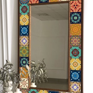 Puede incluir: Un espejo de pared rectangular con un marco de madera marr&oacute;n oscuro decorado con un borde de azulejos cuadrados coloridos. Cada azulejo muestra un patr&oacute;n intrincado inspirado en mandalas en tonos azul, amarillo, rojo, verde y blanco.