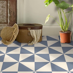 May include: A room with a blue and white geometric patterned floor. A straw hat and a woven basket with a scarf are on the floor. A potted plant with large green leaves is in the corner.