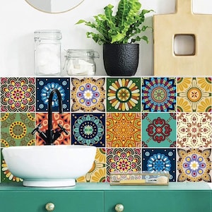 Puede incluir: Un conjunto de azulejos cuadrados para pared con una variedad de coloridos patrones de mandala en tonos azul, amarillo, rojo y verde. Los azulejos est&aacute;n dispuestos en una cuadr&iacute;cula detr&aacute;s de un lavabo de cer&aacute;mica blanca con grifo negro y mueble verde.
