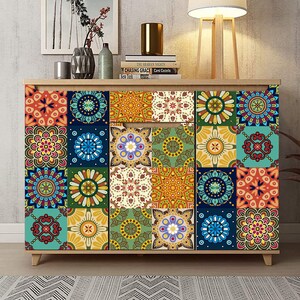 Puede incluir: Un mueble de madera con un panel frontal cubierto por una cuadr&iacute;cula de azulejos cuadrados de colores. Cada azulejo muestra un patr&oacute;n geom&eacute;trico intrincado y &uacute;nico estilo mandala en varios tonos de azul, naranja, amarillo, verde, rojo y blanco.