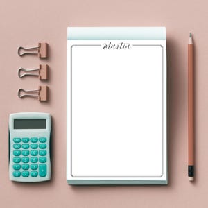 May include: A white notepad with a black border and the word "martin" written in black cursive. The notepad is on a pink surface with a calculator, three binder clips, and a pencil.