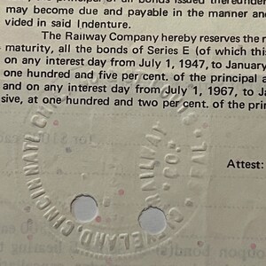 May include: A close-up of a vintage document with text about a European Loan and a Railway Company. The document has a circular stamp with the text "Cincinnati, Ohio" and "NULLA VI", and the word "Attest:" is visible at the bottom right corner.