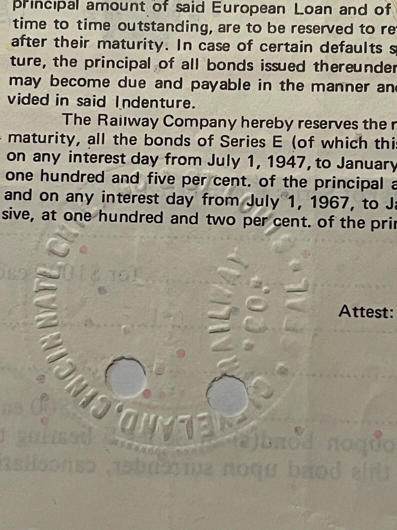 May include: A close-up of a vintage document with text about a European Loan and a Railway Company. The document has a circular stamp with the text "Cincinnati, Ohio" and "NULLA VI", and the word "Attest:" is visible at the bottom right corner.