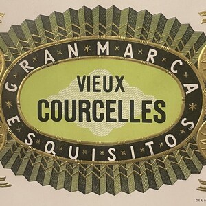 May include: A green and gold cigar band with the text "GRAN*MARCA*ESQUISITOS*" around the outside of an oval. Inside the oval is the text "VIEUX COURCELLES" in white.