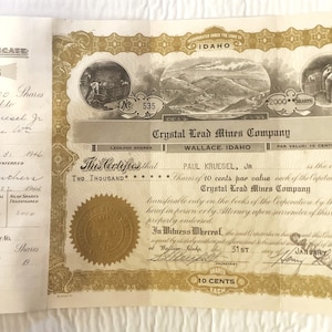 May include: A vintage stock certificate for 2,000 shares of the Crystal Lead Mines Company, dated January 31, 1906, issued to Paul Kruesel Jr. in Wallace, Idaho. The certificate is printed on cream-colored paper with gold lettering and a decorative border.