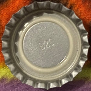 Op de afbeelding: Close-up van een zilveren dop met het nummer "B20" erop gedrukt.