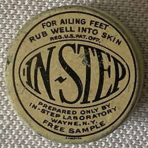 May include: A round, cream-colored tin with black lettering. The text reads "For Ailing Feet Rub Well Into Skin Reg. U.S. Pat. Off. In-Step Prepared Only By In-Step Laboratory Wayne, N.Y. Free Sample".