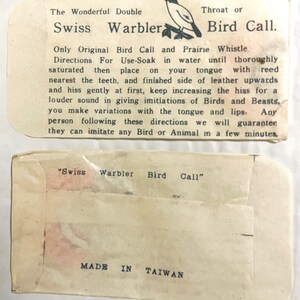 May include: A vintage card for a Swiss Warbler Bird Call. The card features a small bird illustration and text that reads "The Wonderful Double Swiss Warbler Throat or Bird Call. Only Original Bird Call and Prairie Whistle Directions For Use-Soak in water until thoroughly saturated then place on your tongue with reed nearest the teeth, and finished side of leather upwards and hiss gently at first, keep increasing the hiss for a louder sound in giving imitations of Birds and Beasts, you make variations with the tongue and lips. Any person following these directions we will guarantee they can imitate any Bird or Animal in a few minutes." The back of the card reads "Swiss Warbler Bird Call" and "MADE IN TAIWAN."