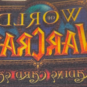 May include: A blue and gold World of Warcraft Trading Card Game logo with the text "World of Warcraft Trading Card Game" in a stylized font.