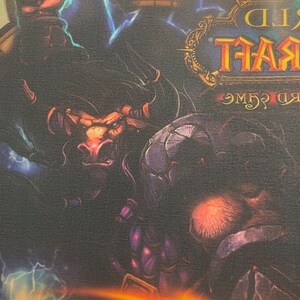 May include: A World of Warcraft mousepad featuring a dark, fantasy-themed illustration of a minotaur-like creature with horns and a red nose, surrounded by lightning bolts and a dark, shadowy figure. The text "World of Warcraft" is visible in the upper right corner.
