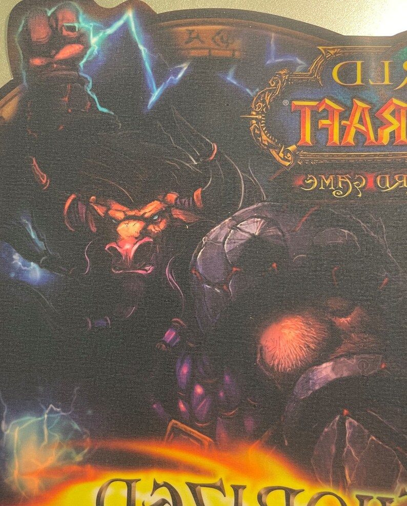 May include: A World of Warcraft mousepad featuring a dark, fantasy-themed illustration of a minotaur-like creature with horns and a red nose, surrounded by lightning bolts and a dark, shadowy figure. The text "World of Warcraft" is visible in the upper right corner.