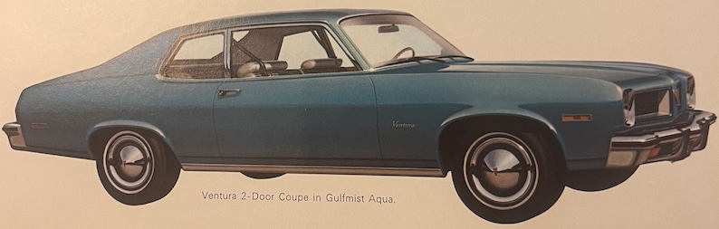 May include: A vintage Gulfmist Aqua Pontiac Ventura 2-Door Coupe. The classic car has a sleek design with chrome accents, white-walled tyres, and a Ventura emblem. The image shows the car's side profile, highlighting its curved roofline and distinctive front end.