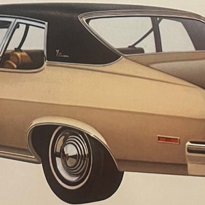 May include: A classic 1974 Ventura Custom Hatchback Coupe in caramel beige. The car has a black roof, chrome detailing, and a unique rear design with rectangular taillights. The image shows the car's side profile.