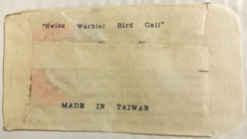 May include: A white paper envelope with the text "Swiss Warbler Bird Call" and "MADE IN TAIWAN" printed on it.