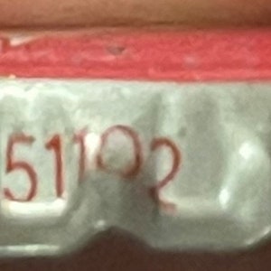 Op de afbeelding: Een zilveren flessen dop met een rode bovenkant. Op de dop staat de tekst "City, Iowa 51102" gedrukt.