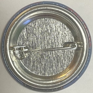 Antique metal pinback button reverse side showing silver clasp pin mechanism closeup