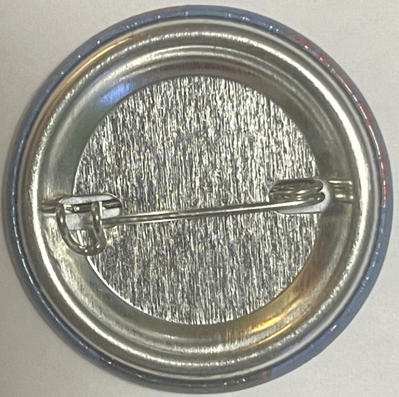 Antique metal pinback button reverse side showing silver clasp pin mechanism closeup