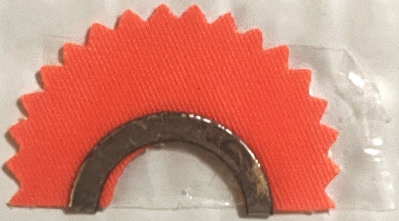 May include: A bright orange fabric target with a silver metal ring in the center. The target is shaped like a half circle with a scalloped edge.