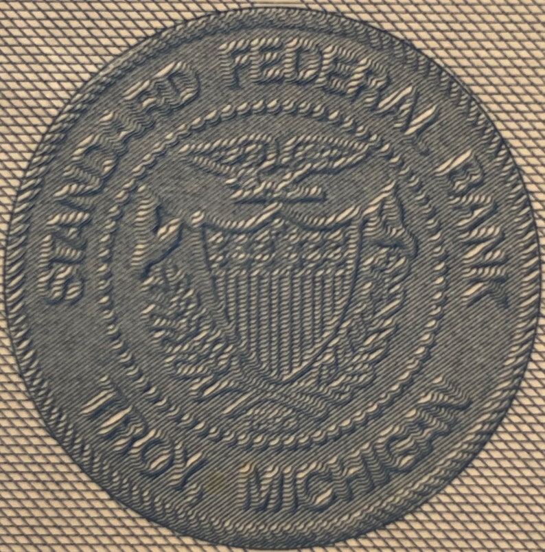 Puede incluir: Un primer plano de un sello azul y blanco con el texto "UNITED STATES FEDERAL RESERVE" y "ONE HUNDRED" alrededor del borde.