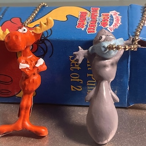 May include: A set of two pull chain light switch covers featuring a red moose and a gray squirrel. The box says "The Adventures of Rocky & Bullwinkle" and "Set of 2".