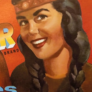 May include: Vintage illustration of a woman with long dark braids wearing a brown headband with a geometric pattern. The woman is smiling and looking to the right. The text "INLAND FRUIT CO. WAPATO, WASHINGTON" is printed below the woman.