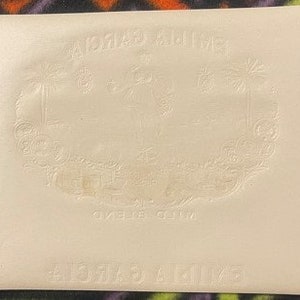 Puede incluir: Una bolsa de cuero blanco con las palabras "A.C.M.A.S. & MILLER" en relieve en la parte delantera. La bolsa tiene un dise&ntilde;o decorativo de palmeras y una ciudad.