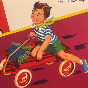 May include: A red wagon with a boy in a blue and white striped shirt and green shorts. The wagon is filled with grapes and has a wooden handle. The boy is smiling and looks like he is having fun.