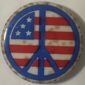 May include: A blue peace sign with a red, white, and blue American flag design. The peace sign is surrounded by a brown, textured border.