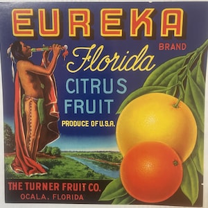 May include: Vintage citrus fruit label with a Native American man playing a flute, a grapefruit, an orange, and the text "EUREKA Florida CITRUS FRUIT PRODUCE OF U.S.A. BRAND THE TURNER FRUIT CO. OCALA, FLORIDA"