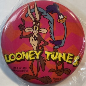 May include: A pink and orange button with a cartoon image of Wile E. Coyote and the Road Runner. The button has the text "LOONEY TUNES" in yellow letters and the text "TM & © 1995 WARNER BROS." in white letters. The button also has the text "Made in China" in white letters.