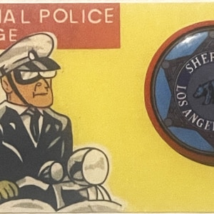 May include: A vintage-style card featuring a cartoon police officer on a motorcycle and a Sheriff badge. The badge is a blue star with the words "SHERIFF LOS ANGELES COUNTY" and a bear emblem. The text "SPECIAL POLICE BADGE" is at the top.