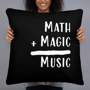 May include: Black throw pillow with white text that reads "MATH + MAGIC = MUSIC".