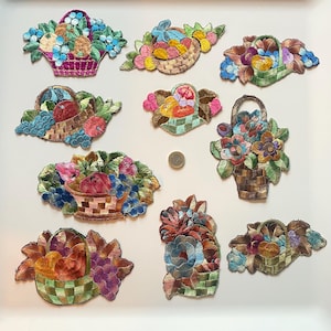 Op de afbeelding: Een verzameling geborduurde patches met manden vol kleurrijke bloemen en fruit. De patches tonen een verscheidenheid aan ontwerpen, waaronder appels, druiven en andere bloemmotieven, met ingewikkelde steken en levendige kleuren.