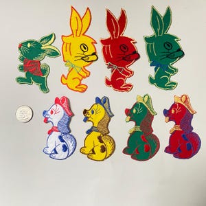 Könnte beinhalten: Acht gestickte Bügelbilder mit Comic-Tieren. Vier Patches sind Hasen in verschiedenen Farben, darunter Gelb, Rot und Grün. Die anderen vier Patches sind Hunde in verschiedenen Farben, darunter Weiß, Gelb, Grün und Rot.
