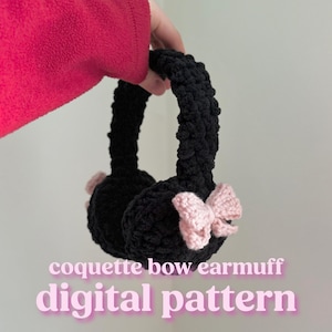 Puede incluir: Orejeras de ganchillo negras con un lazo rosa. Las orejeras están sujetas por una mano. El texto "coquette bow earmuff digital pattern" está en la parte inferior de la imagen.