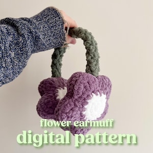 May include: Purple and white crocheted flower earmuffs with green crocheted straps. The earmuffs are held by a hand wearing a blue sweater. The text "flower earmuff digital pattern" is below the earmuffs.