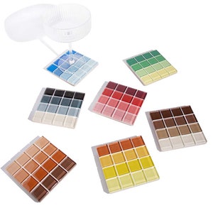May include: Set of six square coasters made of small mosaic tiles. Each coaster features a gradient of colors, including blue, green, red, brown, orange, and yellow.