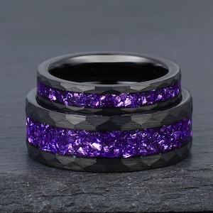 May include: Two black tungsten carbide rings with a purple crushed amethyst inlay. The rings are stacked on top of each other.