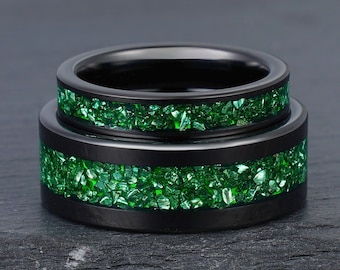 May include: Two black tungsten carbide rings with a green crushed glass inlay. The rings are stacked on top of each other.