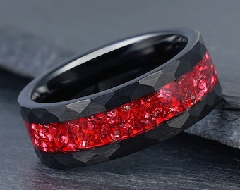 Peut inclure: Une bague en carbure de tungstène noir avec une incrustation de pierres précieuses rouges. La bague a une finition texturée et martelée.