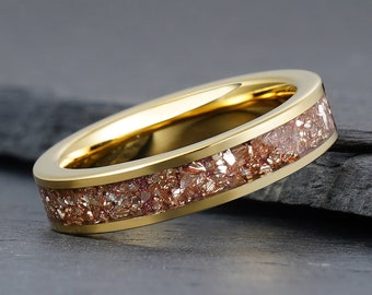 Könnte beinhalten: Ein goldener Ring mit einem Band aus eingebetteten, glitzernden, kupferfarbenen Partikeln.