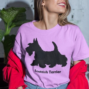 May include: A woman wearing a light purple t-shirt with a black silhouette of a Scottish Terrier and the text "Scottish Terrier".