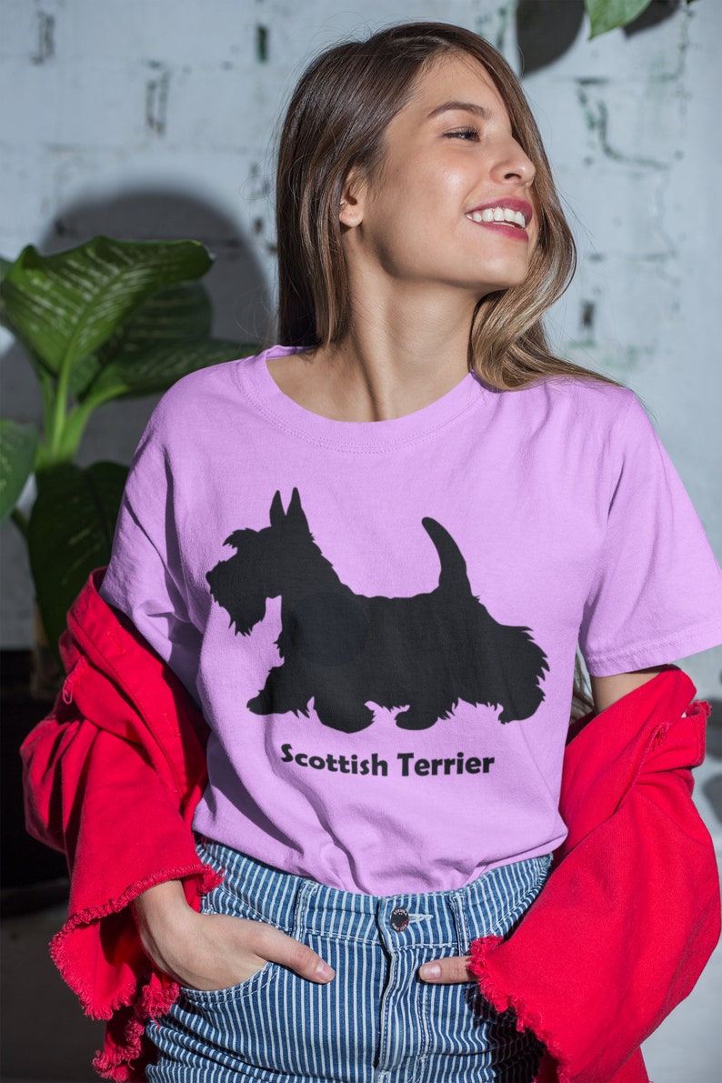 May include: A woman wearing a light purple t-shirt with a black silhouette of a Scottish Terrier and the text "Scottish Terrier".
