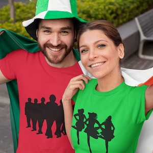 May include: Two people wearing red and green t-shirts with silhouettes of Irish dancers and musicians. They are holding an Irish flag.