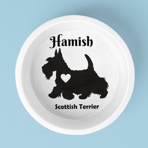 May include: White ceramic dog bowl with a black silhouette of a Scottish Terrier with a heart on its chest. The bowl is personalized with the name "Hamish" and the breed "Scottish Terrier".